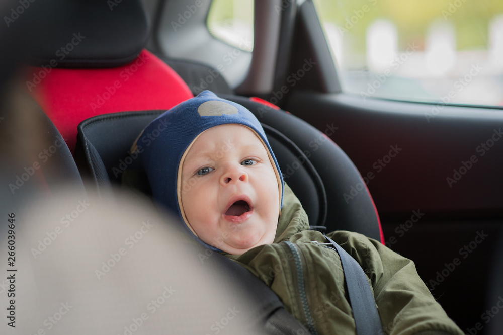 Close Up caucasian cute baby boy woke up and yawns in modern car seat. Child traveling safety on the road. Safe way to travel fastened seat belts in a vehicle with young kids. Trip with toddler. Close Up caucasian cute baby boy woke up and yawns in modern car seat. Child traveling safety on the road. Safe way to travel fastened seat belts in a vehicle with young kids. Trip with toddler.