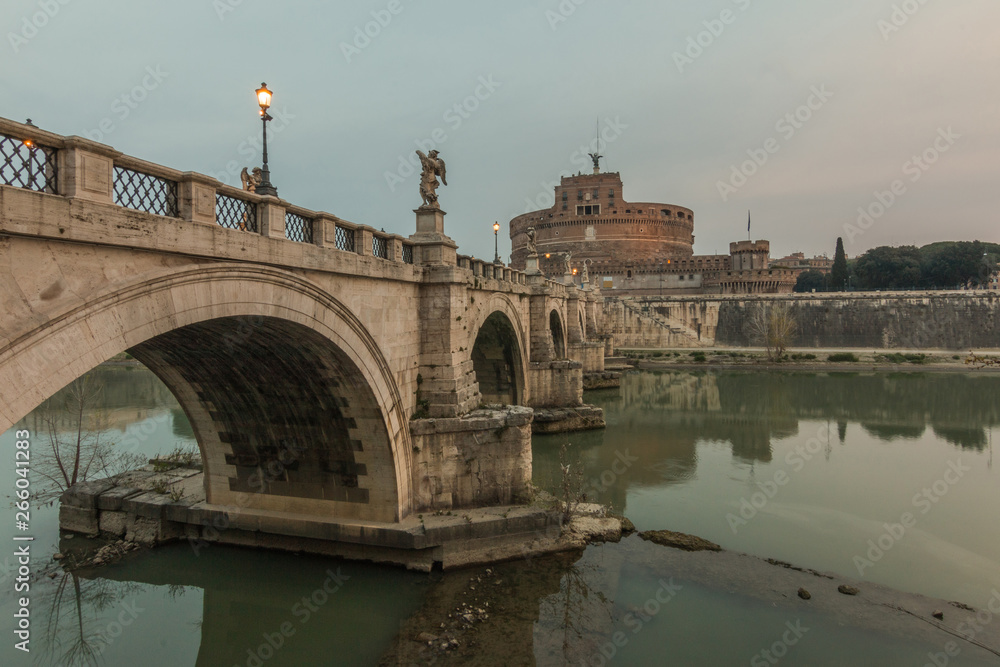 Aurelius bridge with the Castle Sant'Angelo in the morning at dusk in the center of the historic center of Rome. Historic streets. Lighting on the bridge over the river Tiber in Rome at side view
