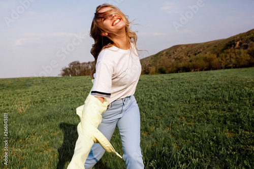 Outdoors lifestyle fashion portrait of happy smilling blonde girl. Beautiful smile. Long curly light hair. Wearing stylish yellow jacket and jeans. Joyful and cheerful woman. Happiness photo