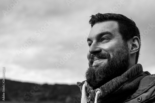 Tableau sur toile Young attractive bearded man with dark hair and a pullover in the park smiling