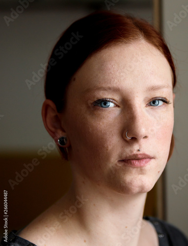 young pretty ginger girl with blue eyes looking sorrowful out of the window