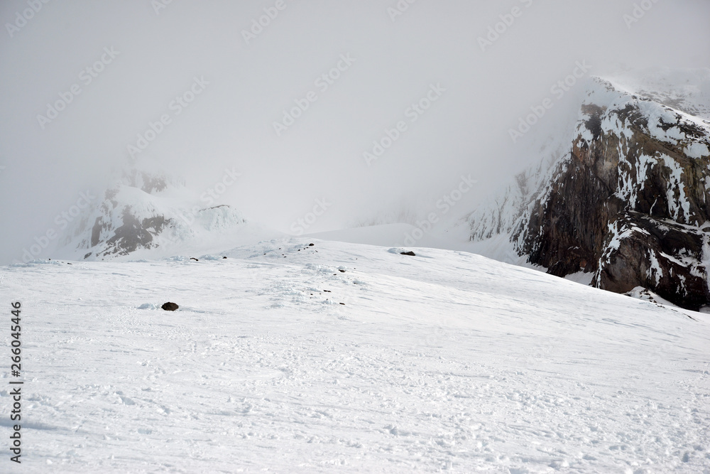 Fototapeta premium Snow covered terrain on Mount Hood, a volcano in the Cascade Mountains in Oregon popular for hiking, climbing, snowboarding and skiing, despite risks of avalanche, crevasses and weather on the peak.
