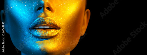 Fashion model woman face in bright sparkles, colorful neon lights, beautiful sexy girl lips. Trendy glowing gold skin make-up. Wide screen © Subbotina Anna