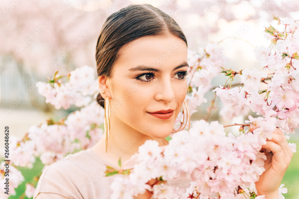 Outdoor portrait of beautiful 18-20 year old girl posing in blooming garden