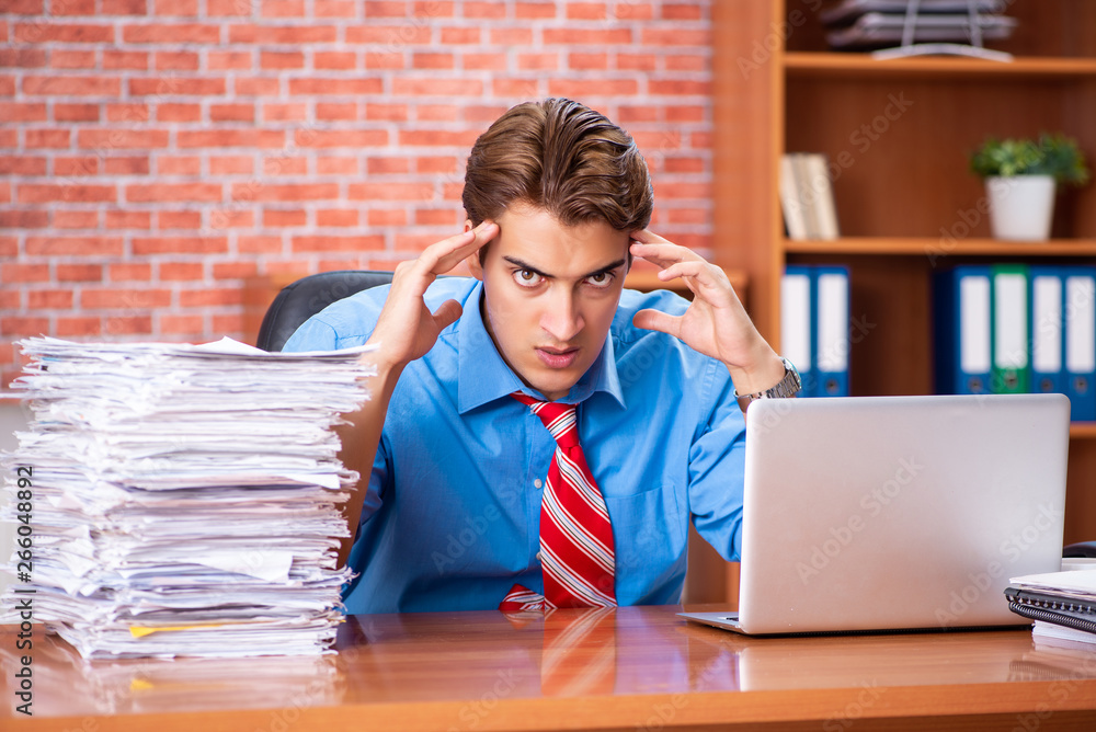Young employee with excessive work sitting at the office Young employee with excessive work sitting at the office