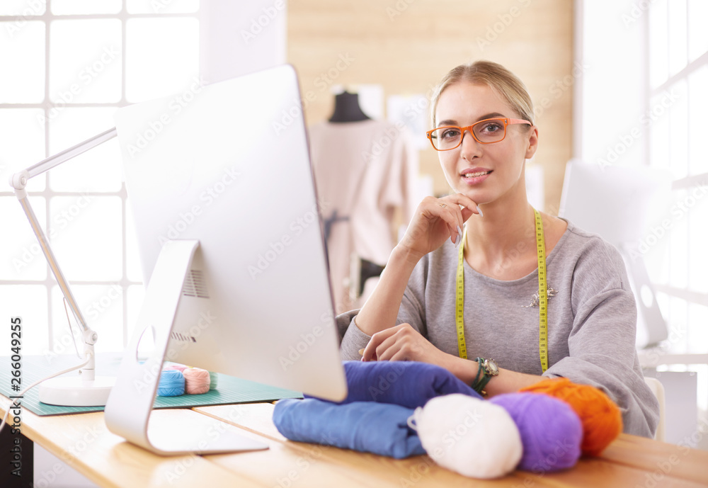 Fashion designer woman working in studio, sitting at thhe desk Fashion designer woman working in studio, sitting at thhe desk