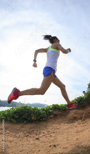 Woman trail runner running on seaside hills