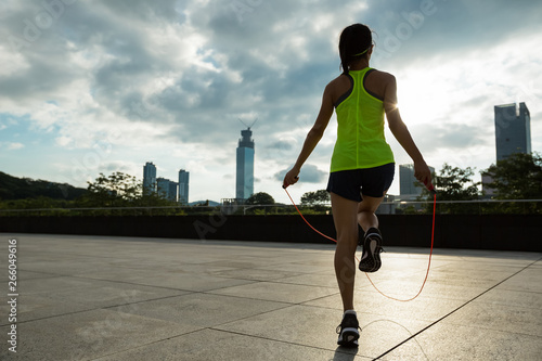 Canvas Print young fitness woman jumping rope on city