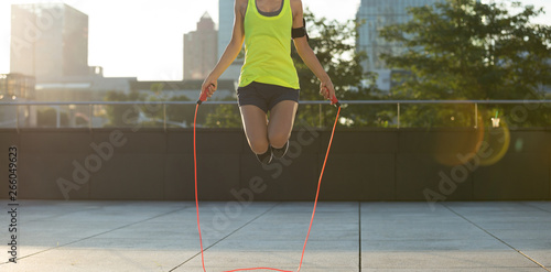 Obraz na plátně young fitness woman jumping rope on city