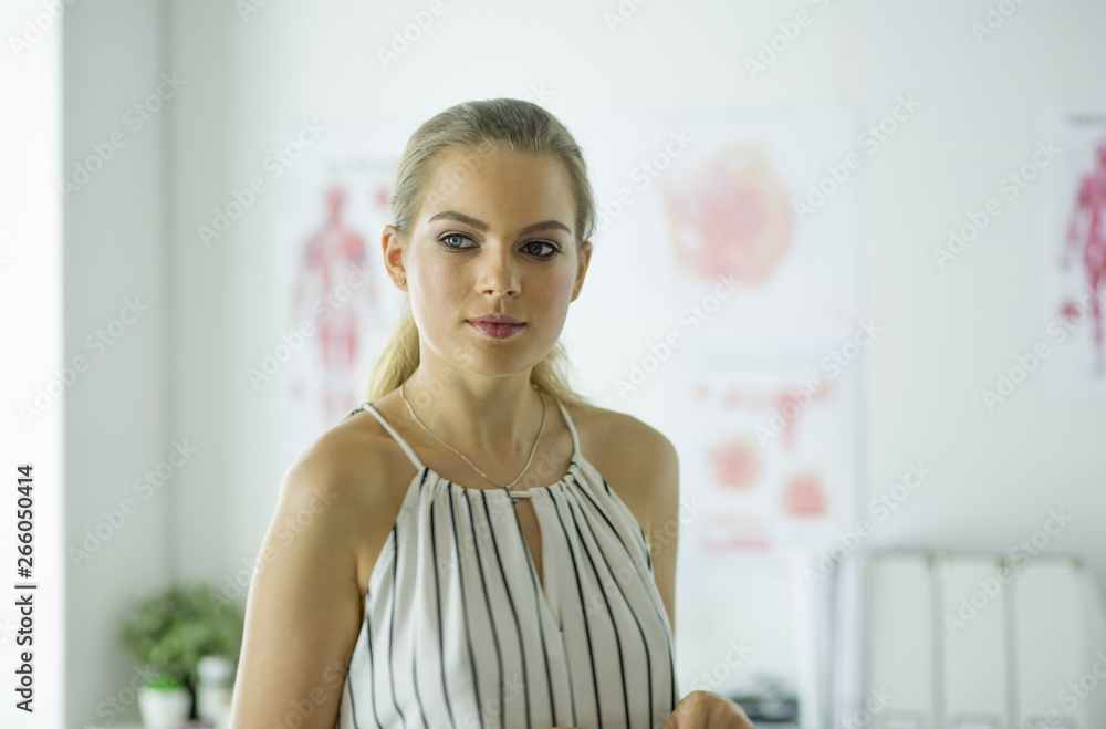 Portrait of happy young smiling girl doctor. Evenly standing in a white medical office