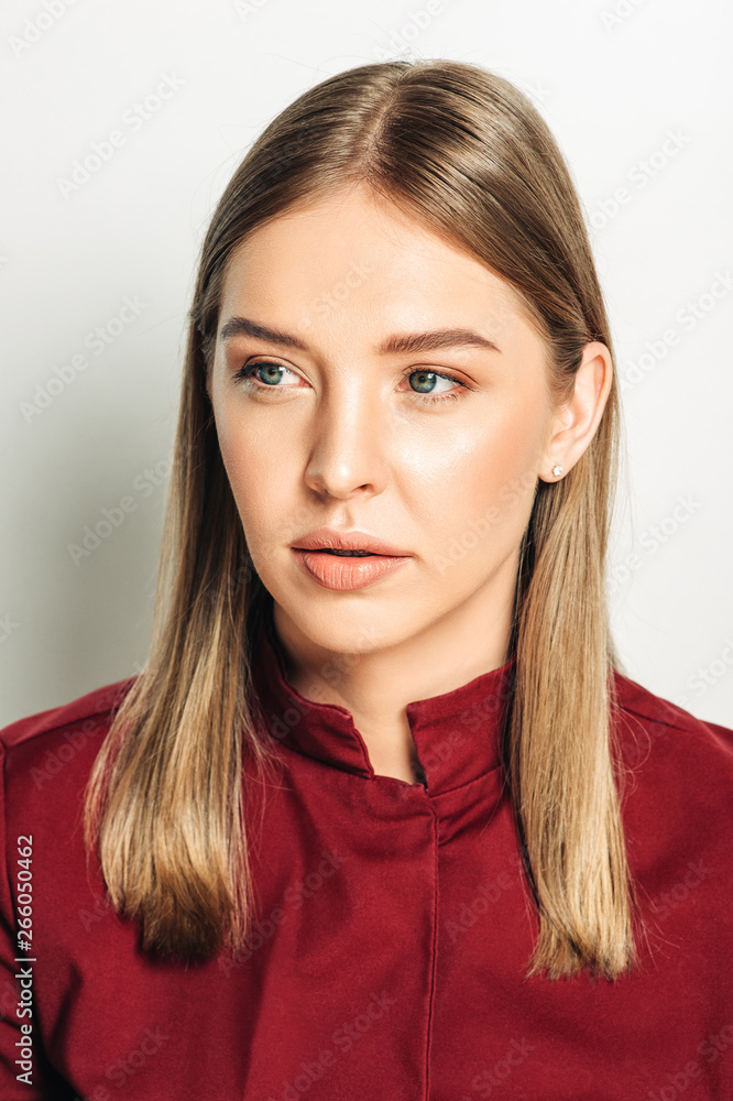 Close up portrait of beautiful young woman with blond hair, wearing red high neck jacket, nude makeup Close up portrait of beautiful young woman with blond hair, wearing red high neck jacket, nude makeup