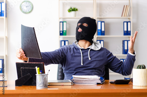 Male thief in balaclava in the office 