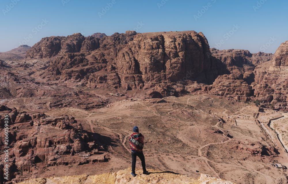 Traveler standing on cliff enjoying desert sightseeing in Petra, Jordan