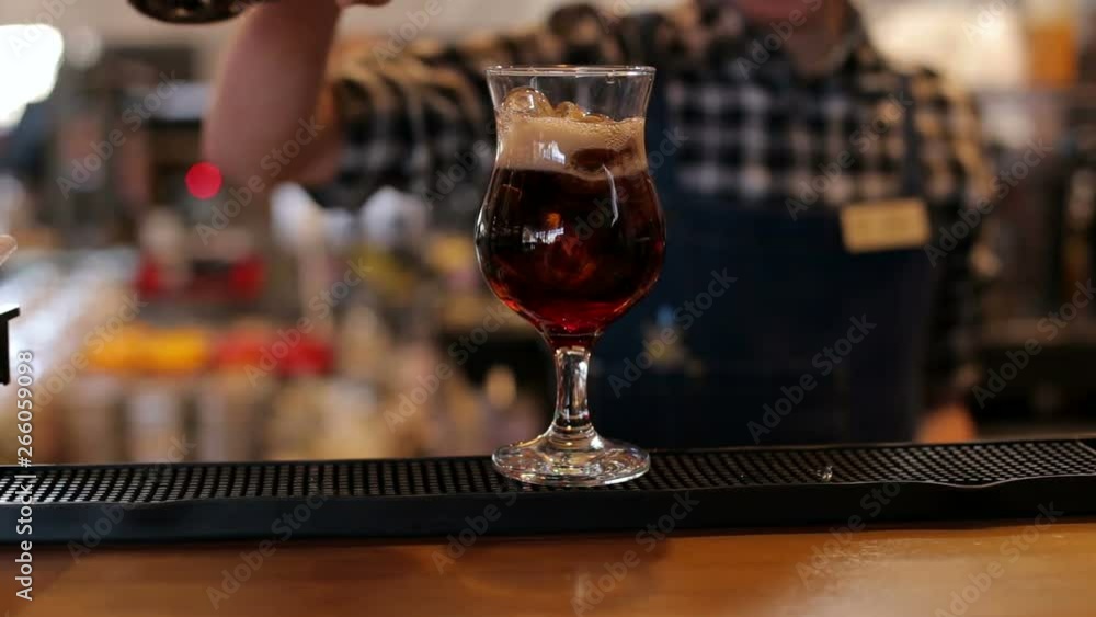The bartender pours a coke into an empty glass of ice in the bar. Preparation of cocktails at the bar. Professional bartender's hands make drinks in night club bar. The bartender pours a coke into an empty glass of ice in the bar. Preparation of cocktails at the bar. Professional bartender's hands make drinks in night club bar.