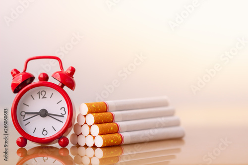 Cigarettes stack and red alarm clock. World no tobacco day. Cigarette and family figure. a concept for stop smoking. Smoking a cigarette can kill everyone in family. Save family from smoking. photo