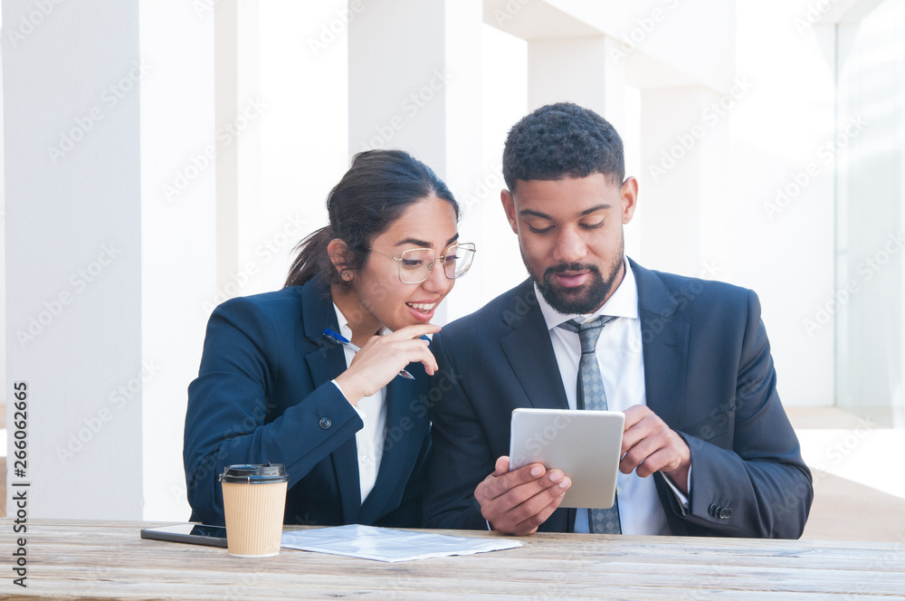 Surprised business people working on tablet computer at desk. Business man and woman wearing formal clothes and sitting at cafe table. Business work concept. Front view. Surprised business people working on tablet computer at desk. Business man and woman wearing formal clothes and sitting at cafe table. Business work concept. Front view.