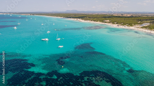 Amazing drone aerial landscape of the charming beach Es Trencs and the boats with a turquoise sea. It has earned the reputation of Caribbean beach of Mallorca. Spain