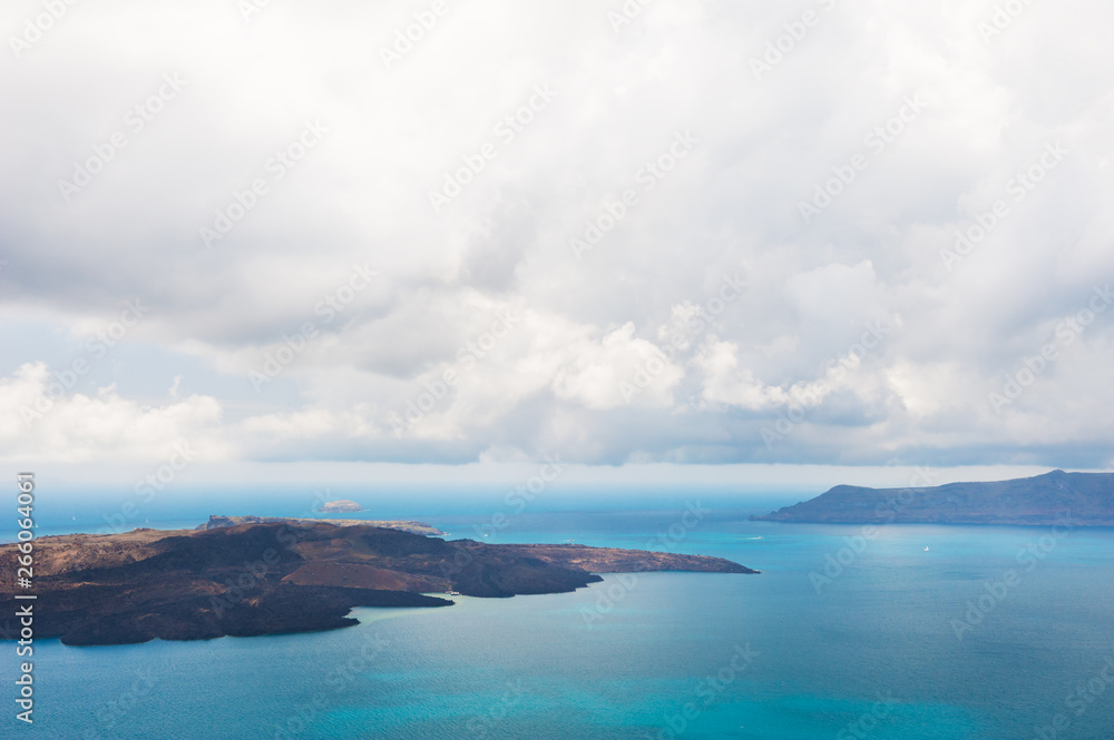 Stormy clouds over the sea. View of Nea Kameni volcano island near Santorini island, Greece