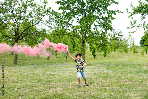 Young boy running trailing a pink smoke flare