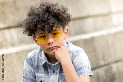 Foto Serious young boy in yellow sunglasses