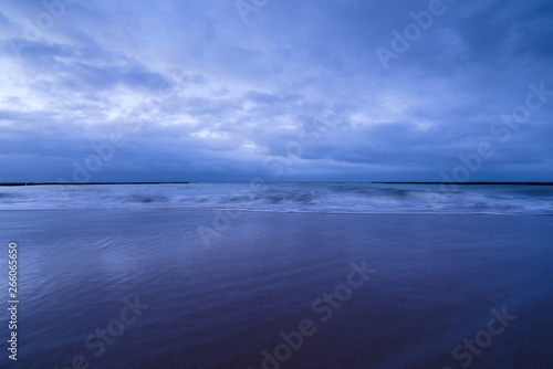 Sunset on the beach with waves against a dramatic blue cloudy sky  baltic sea  Usedom