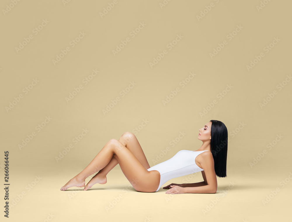 Naklejka premium Attractive and sporty woman posing in white swimsuit. Fit and athletic body. Beautiful girl in swimsuit. Fitness, diet and weight loss concept.