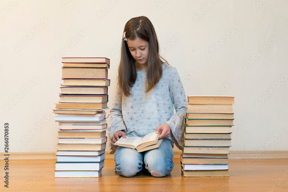 Girl reading a book sitting on the floor in an apartment. Cute girl reading book at home. education and school concept - little student girl sitting on floor and reading book Girl reading a book sitting on the floor in an apartment. Cute girl reading book at home. education and school concept - little student girl sitting on floor and reading book