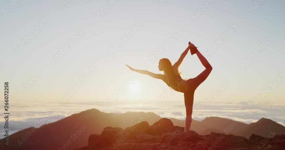 Young athletic woman performing yoga pose on the top of a mountain at sunrise, zen wellness woman performs dancer's pose