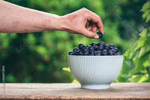 Blueberries in a bowl on wooden table and a psoriasis hand photo