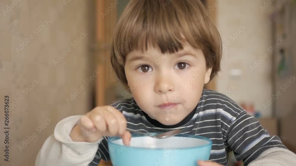 Little boy having Breakfast at home. Pretty American boy eating cereal with appetite. Child having breakfast in the kitchen. Closeup. Little boy having Breakfast at home. Pretty American boy eating cereal with appetite. Child having breakfast in the kitchen. Closeup.