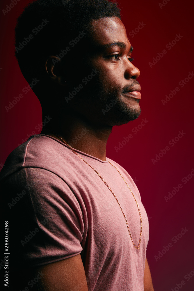 Fototapeta premium Serious black Afro American man with thoughtful expression looking directly into camera while posing against dark studio wall. Grave businessman in t-shirt planning his working day schedule