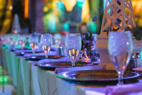 Elegant Plates and Crystal Wine Glasses set at Long Tables during an Event with Purple lighting