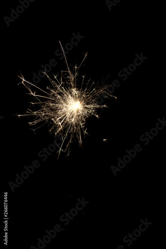 Burning squib on a black background with sparks.