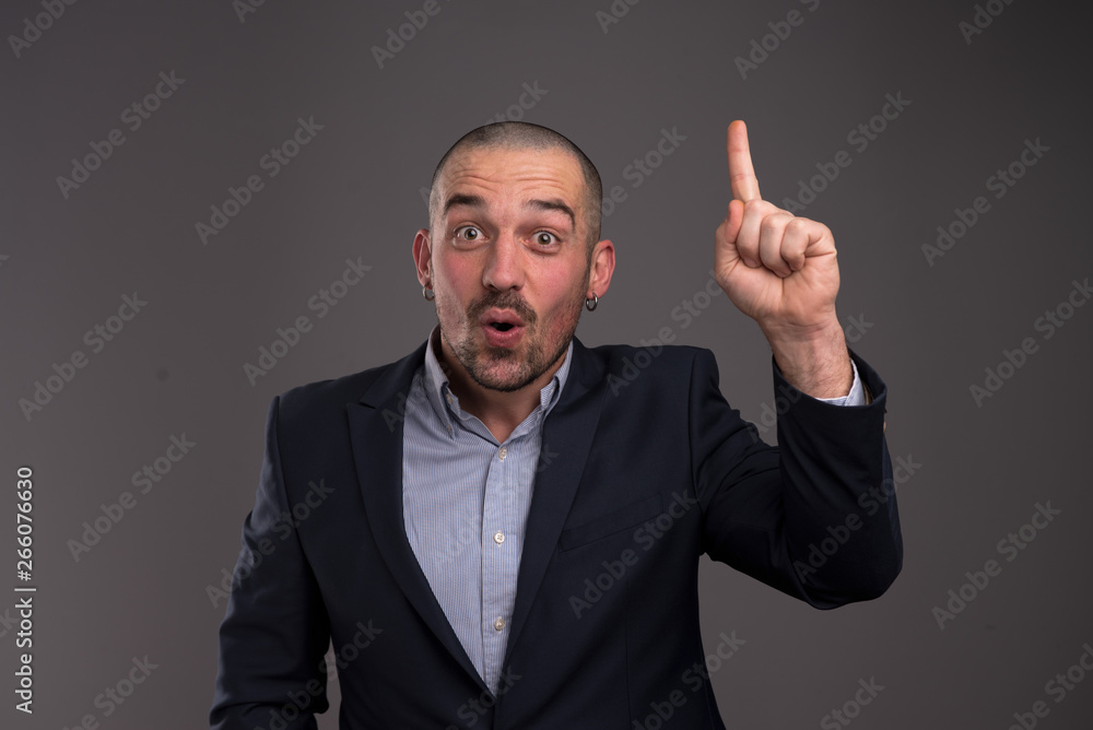 Portrait of surprised charismatic man with his forefinger pointed upwards Portrait of surprised charismatic man with his forefinger pointed upwards