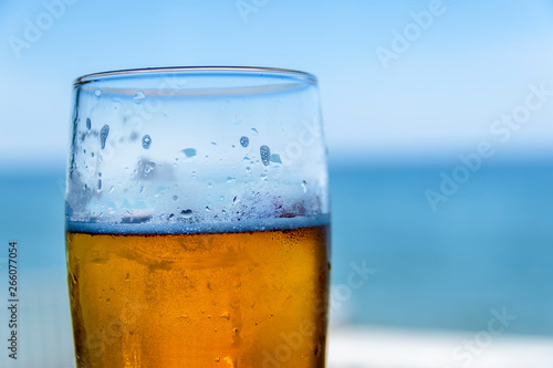 Misted glass of beer on the background of the sea landscape. 