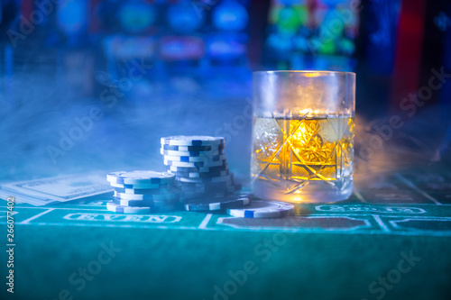 gambling, fortune, game and entertainment concept - close up of casino chips and whisky glass on table photo