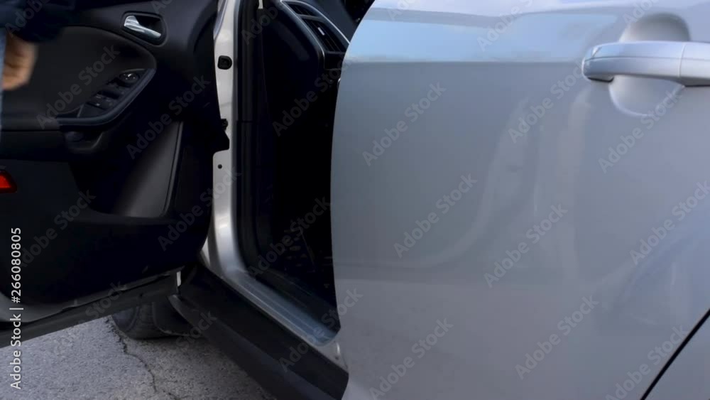 Young man gets out of a silver car Young man gets out of a silver car