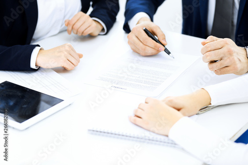 Group of business people and lawyers discussing contract papers sitting at the table, close-up. Successful teamwork, cooperation and agreement concepts
