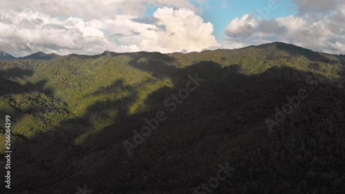 Aerial moving left shot over the lush green mountains with the shadow of clouds in the Coromandel Peninsula New Zealand photo