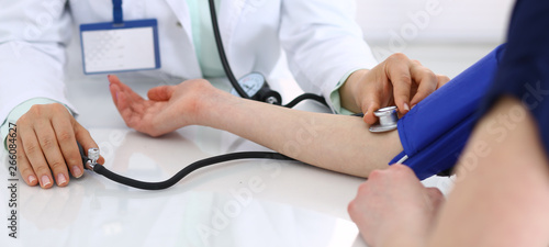 Unknown doctor woman checking blood pressure of female patient, close-up. Cardiology in medicine  and health care concept photo