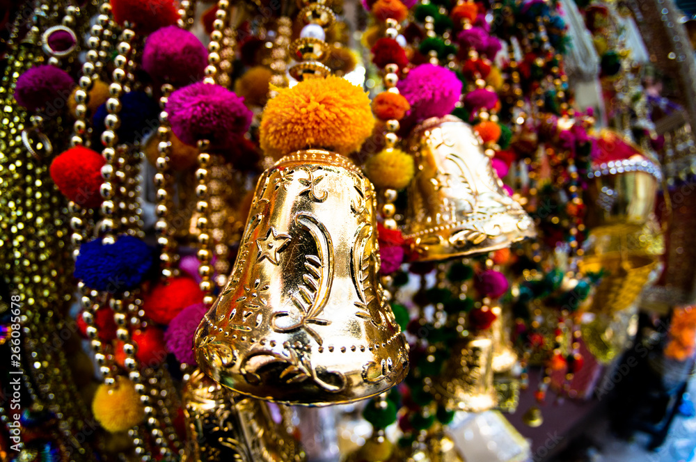 Fototapeta premium Dangling golden decorations with bells and puffs hanging in a store in chandni chowk delhi