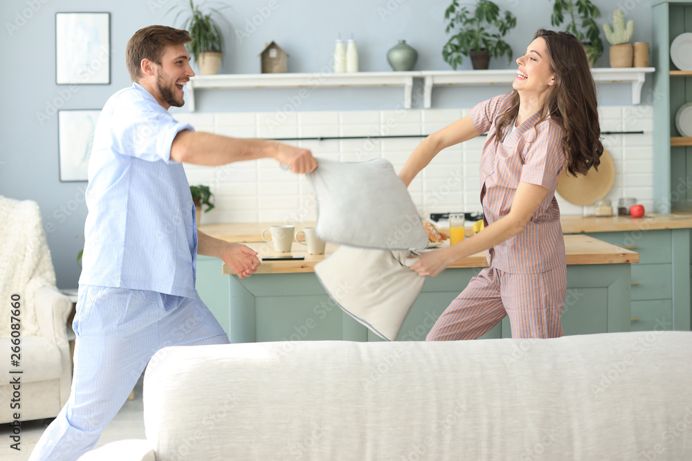 Fototapeta premium Happy loving couple having fun while having a pillow fight in the living room.