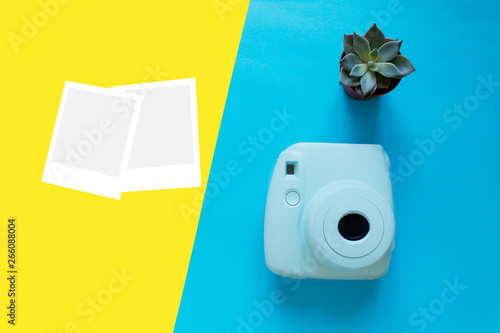 Blue camera with blank picture frames on colourful background. Fashion Film Camera. Nostalgia photography. Top view. Minimal and modern design. Trendy flat lay mockup for bloggers, designers, etc. 