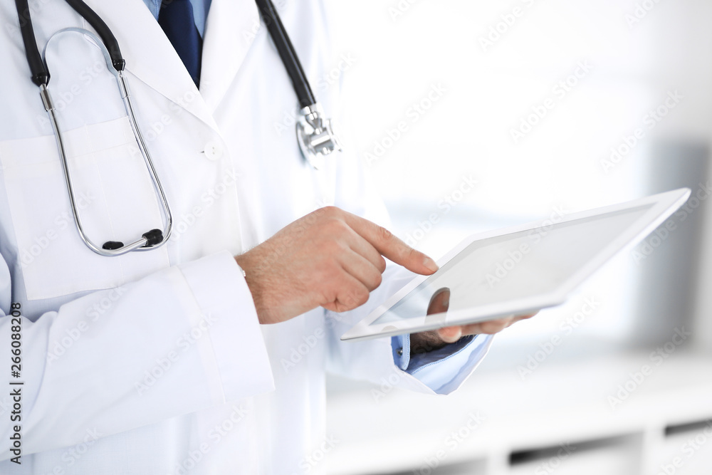 Doctor man using tablet computer for network research or virtual disease treatment, hands close-up. Perfect medical service in clinic. Modern medicine, medic data and healthcare concepts Doctor man using tablet computer for network research or virtual disease treatment, hands close-up. Perfect medical service in clinic. Modern medicine, medic data and healthcare concepts