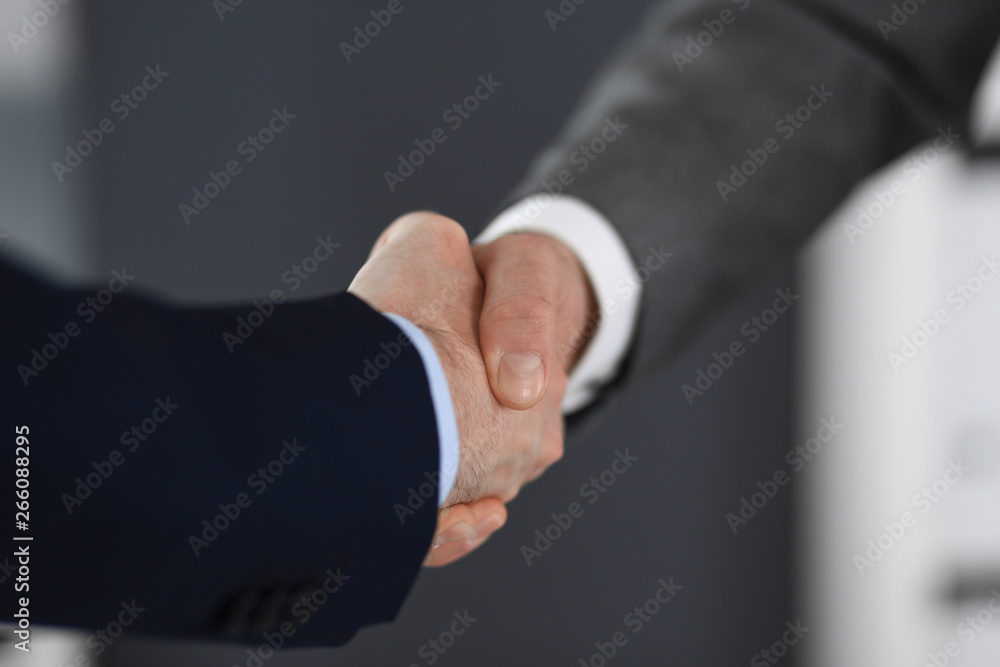 Business people shaking hands at meeting or negotiation in modern office, close-up. Teamwork, partnership and handshake concept