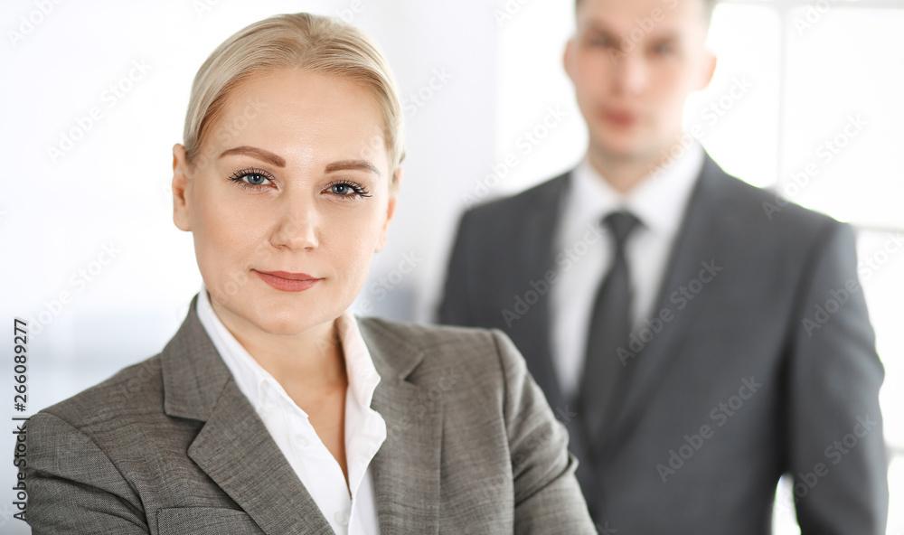 Business woman standing straight with colleague businessman in office, headshot. Success and corporate partnership concept Business woman standing straight with colleague businessman in office, headshot. Success and corporate partnership concept
