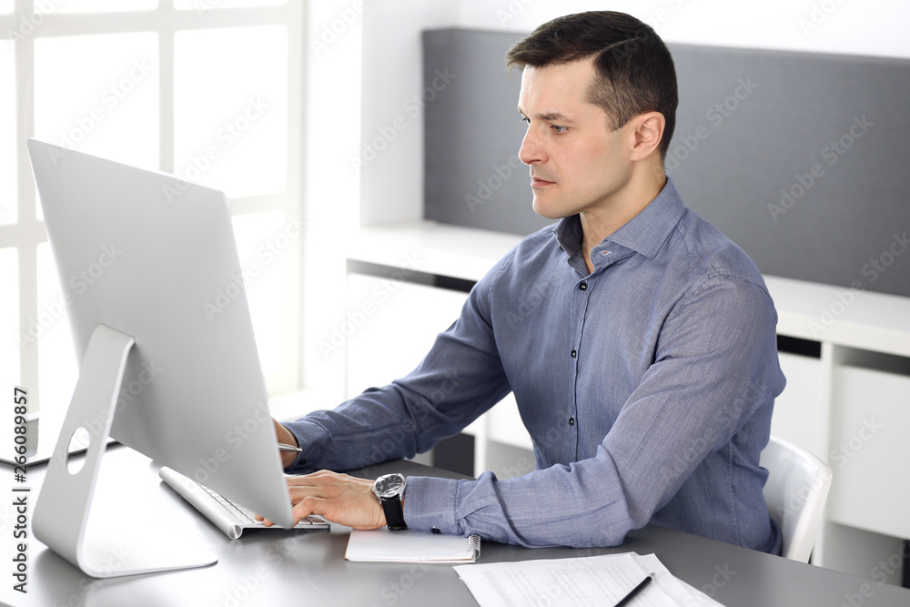Businessman working with computer in modern office. Headshot of male entrepreneur or company director at workplace. Business concept Businessman working with computer in modern office. Headshot of male entrepreneur or company director at workplace. Business concept