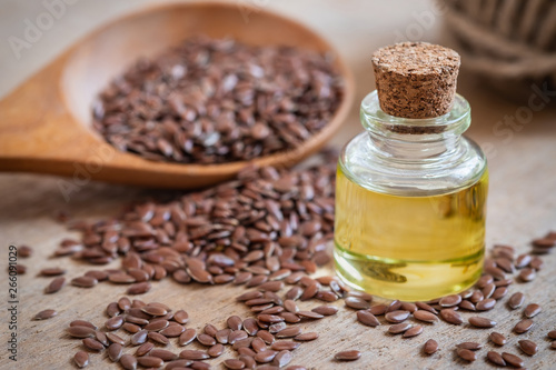 Flaxseed oil in bottle and brown flax seeds on wooden spoon