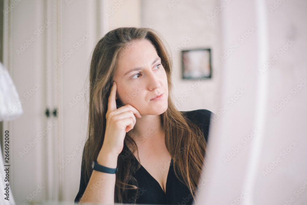 Close-up girl of European appearance thoughtfully sits in front of a mirror in a bright hotel room Close-up girl of European appearance thoughtfully sits in front of a mirror in a bright hotel room