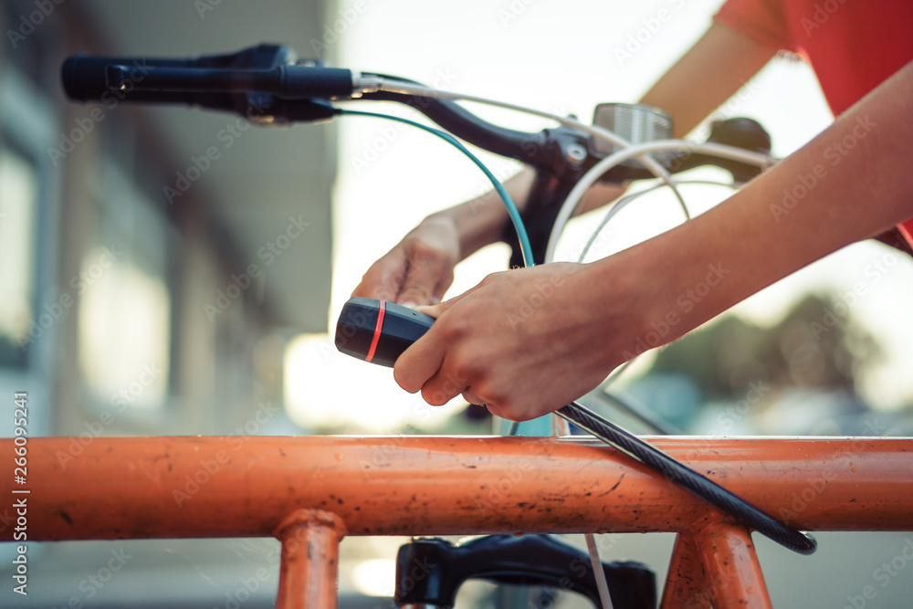 Girl teenager fastening bicycle lock on street parking at sunset Girl teenager fastening bicycle lock on street parking at sunset